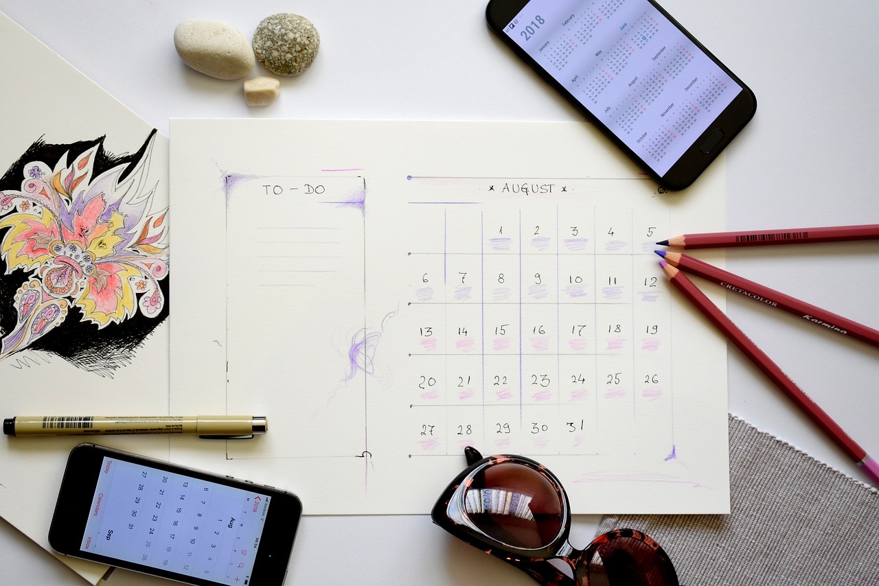 A hand-drawn monthly calendar with phones and colored pencils